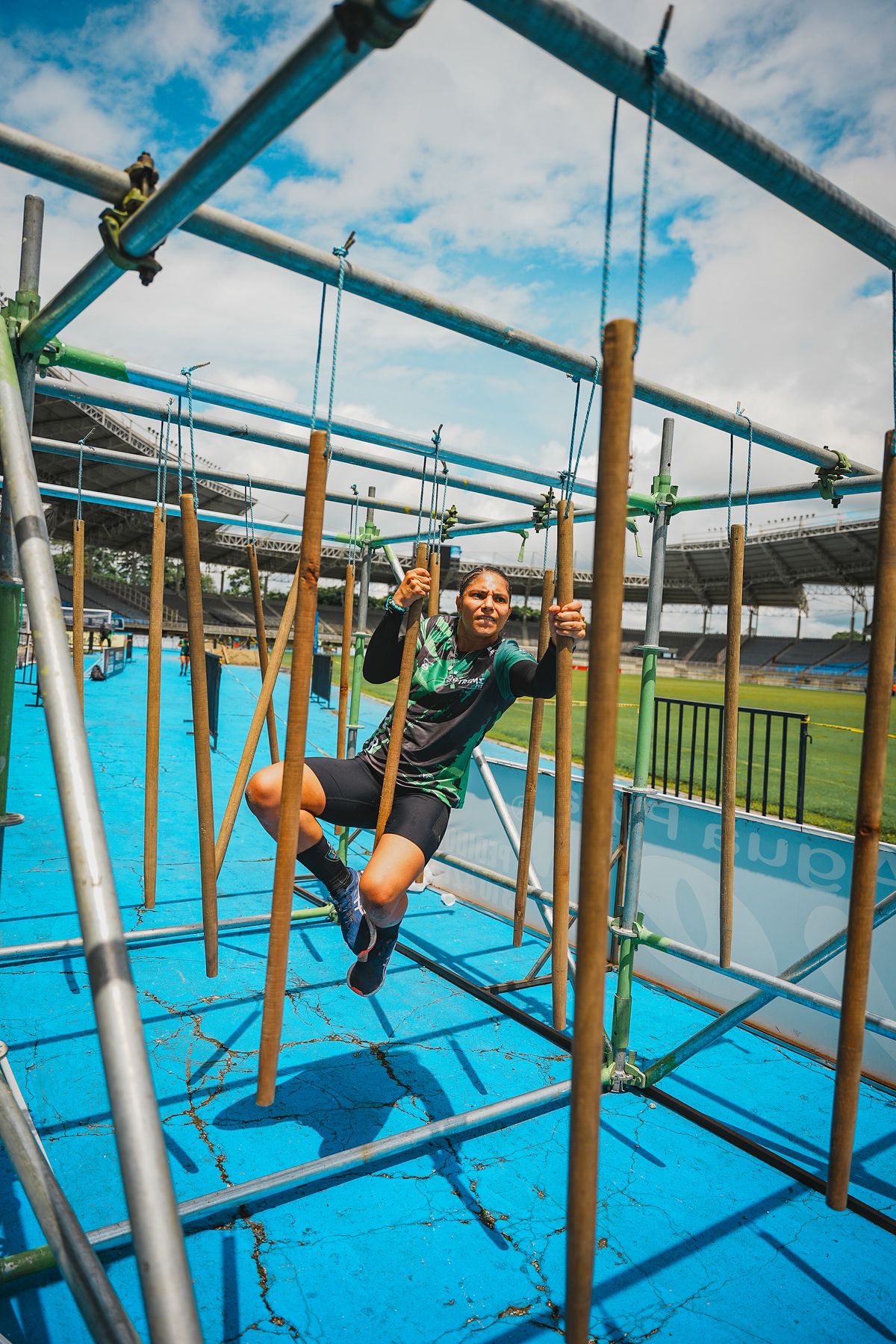 Athlete swinging across hanging poles on an obstacle course